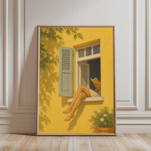 Op de afbeelding: Een ingelijste muurkunstprint met een gele buitenmuur met een raam, een lichtgroene luik en een potplant met witte bloemen. Een paar benen in een wit kledingstuk rust op de vensterbank terwijl een open geel boek wordt vastgehouden.
