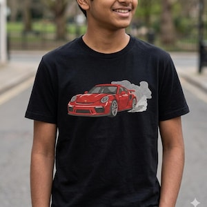 May include: Black t-shirt featuring a red sports car graphic with white smoke detail. The car design is detailed with headlights, wheels, and a spoiler. The shirt is a classic crew neck style.