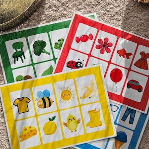 May include: Four colorful educational flashcards with various illustrations. The cards are in green, red, yellow, and blue. Each card features a grid of images, including a chair, broccoli, a ladybug, a banana, a car, and an ice cream cone.