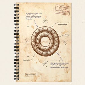 May include: Spiral-bound notebook with a vintage design. The notebook features a detailed illustration of a circular object with ancient symbols, labeled with handwritten notes and diagrams. The words "Classified Specimen" are stamped at the top.