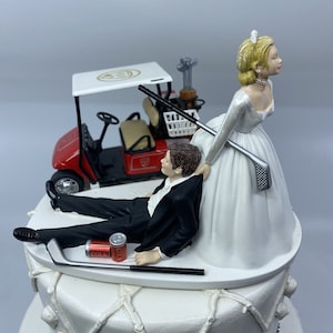 ゴルフなしの赤いゴルフカートのウェディングケーキトッパーを持つ新郎新婦面白い