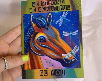 May include: A colorful card with a brown horse head and blue dragonfly illustrations. The text on the card reads "Be Strong Be Beautiful Be You".