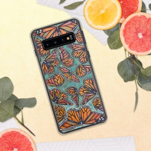 May include: A clear phone case featuring a vibrant design of orange and black monarch butterflies on a teal background. The case has a black border and the artist's signature, @SammWehmanArt, is visible at the bottom.