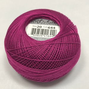 Può includere: Un gomitolo di filo da ricamo rosa scuro, taglia 20, colore 644, con un'etichetta che riporta "Lizbeth" e il codice prodotto 69826 41644. L'etichetta indica anche 25g = 210 yards.