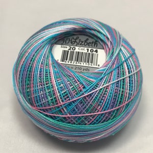 Può includere: Un gomitolo di filo da uncinetto multicolore nei toni del blu, rosa, verde e bianco. L'etichetta recita "HH Lizbeth Size 20 Col. 104". Il filo è ben avvolto e i colori sono distribuiti uniformemente.