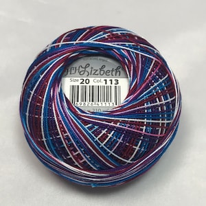 Può includere: Un gomitolo di filo da uncinetto multicolore, con sfumature di blu, viola, rosa e bianco. L'etichetta recita "Lizbeth" e "Size 20 Col. 113". Il filo è mercerizzato e bruciato, con un totale di 192 metri.