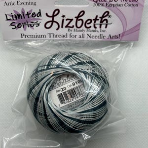 Può includere: Un gomitolo di filo Lizbeth taglia 20 in una confezione di plastica trasparente. Il filo è un mix di verde acqua scuro, argento e bianco. La confezione include il testo "Artic Evening", "Limited Series" e "100% Egyptian Cotton".