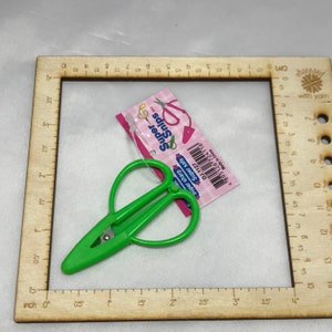 May include: Green heart-shaped scissors with a silver blade. The scissors are 2 inches long and are labeled "Super Snips" with the text "Super Sharp" and "Super Safe".