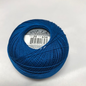Op de afbeelding: Een blauwe bol borduurgaren met een label waarop staat "H.J.Lizbeth Maat 20 Col. 656" en een barcode. Het label vermeldt ook "25g = 210m".