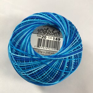Puede incluir: Una madeja de hilo de bordar azul, azul claro y blanco con una etiqueta que dice "DMC Elizabeth Size 20 Col. 149 25g = 210 yds."