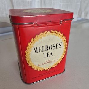May include: A vintage red rectangular tea tin with the text "MELROSE'S TEA" in a gold wreath. The tin contains 250 grams of tea. The tin is blended and packed by Melrose's Ltd, Edinburgh, Scotland.