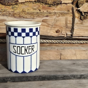 Peut inclure: Une tasse en céramique blanche avec une anse noire et le texte "But First, Coffee" en noir, en gras. La tasse est posée sur une surface blanche.