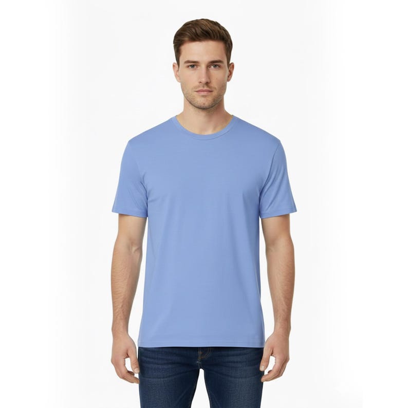 May include: A light blue crew neck t-shirt. The short-sleeved shirt is made of a soft material. The model is wearing blue jeans. The background is white.