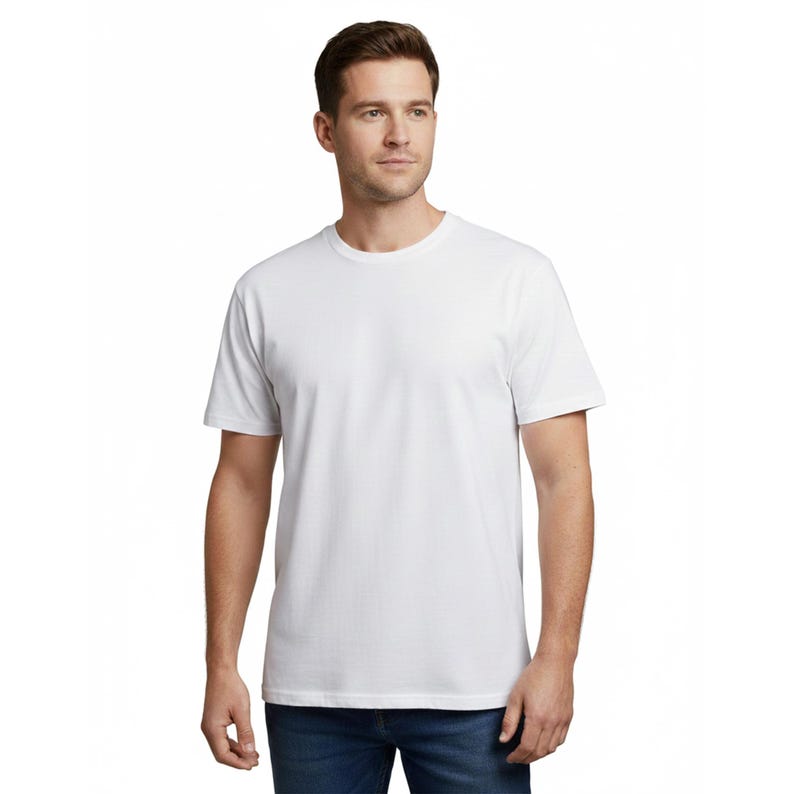 May include: A plain white crew neck t-shirt. The short-sleeved shirt is made of a soft material and is worn by a person wearing blue jeans. The shirt has a classic, simple design.