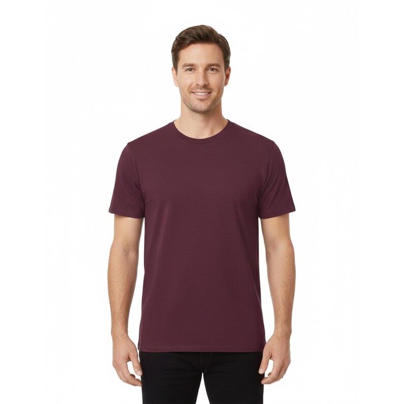 May include: A maroon crew neck t-shirt. The short-sleeved shirt is made of a soft material and is worn by a person. The shirt has a classic, simple design, suitable for casual wear. The background is white.