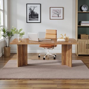 May include: A modern home office setup featuring a light brown wooden desk with a laptop, a tan leather office chair, and decorative items. The room includes a beige rug, a potted plant, and framed artwork on the wall.