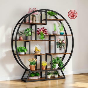 May include: A black metal and wood plant shelf with a circular design. The shelf has multiple levels with various potted plants and flowers. The structure is supported by a base and features a "Free Shipping" sticker.