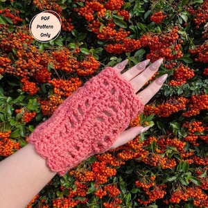 Puede incluir: Un guante sin dedos de ganchillo de color coral con un borde festoneado. El guante presenta un diseño calado. El fondo es un arbusto con hojas verdes y racimos de bayas naranjas. Un gráfico circular dice "PDF Pattern Only".