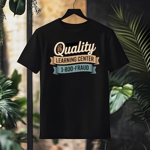 Könnte beinhalten: Schwarzes T-Shirt mit dem Text "Quality Learning Center 1-800-FRAUD" in einem Vintage-Design. Das Design enthält ein Haus-Symbol und Banner-Elemente in Beige und Blau. Das T-Shirt hängt an einem schwarzen Kleiderbügel.