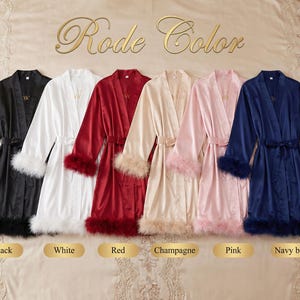 May include: Satin robes in black, white, red, champagne, pink, and navy blue, each with a matching belt and feather trim on the cuffs and hem. The robes are displayed on a bed.