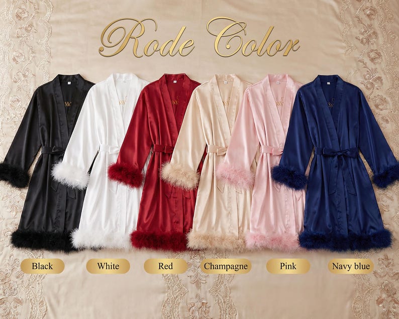 May include: Satin robes in black, white, red, champagne, pink, and navy blue, each with a matching belt and feather trim on the cuffs and hem. The robes are displayed on a bed.