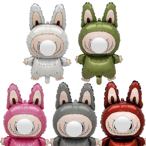 May include: Party Balloons text above a collection of six foil balloons shaped like cartoon characters. The balloons are in various colors: white, green, pink, gray, and red. Each balloon has a large, round face with a white circle and a toothy grin.