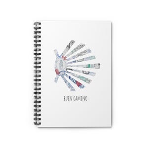 May include: White spiral-bound notebook with a stylized hand design made of various patterned elements. The phrase "BUEN CAMINO" is printed in black at the bottom of the notebook.