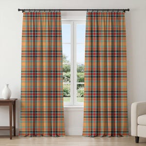 Puede incluir: Dos cortinas estampadas a cuadros en tonos naranja, verde azulado, rojo y negro cuelgan de una barra negra frente a una ventana. Una pequeña mesa de madera con un jarrón blanco se encuentra a la izquierda de la ventana. Un sofá blanco está a la derecha.