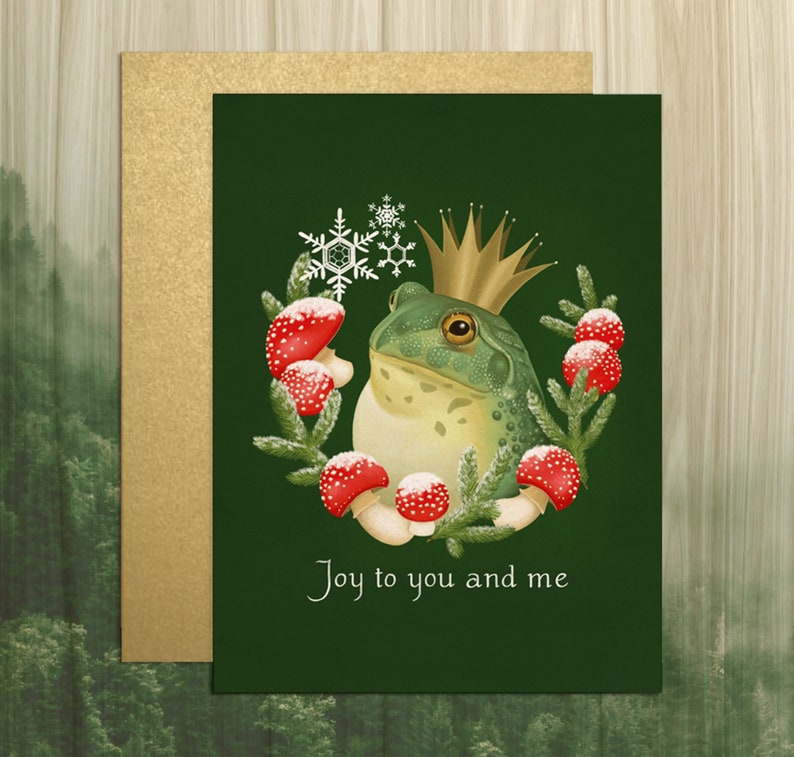 Illustrated portrait of a bullfrog, in tones of green and yellow, wearing a simple gold crown. The frog is encircled by a three quarters round wreath made of red amanita mushrooms, spruce sprigs, and snowflakes. Solid green background.