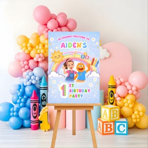 Puede incluir: Un letrero de fiesta de cumpleaños sobre un caballete de madera, con el texto "Hi Friends! Welcome to Aiden's 1st Birthday Party." El letrero presenta un arcoíris, un sol y personajes de dibujos animados, rodeados de globos y bloques decorativos.