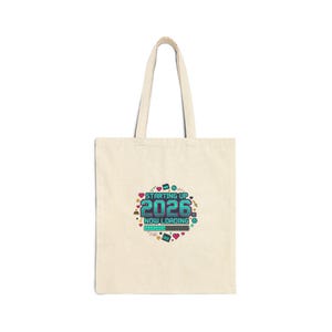 May include: A cream-coloured tote bag featuring the text "STARTING UP 2026 NOW LOADING" in teal and white, with heart and pixelated graphics. The bag has a simple design with a handle, suitable for carrying items.