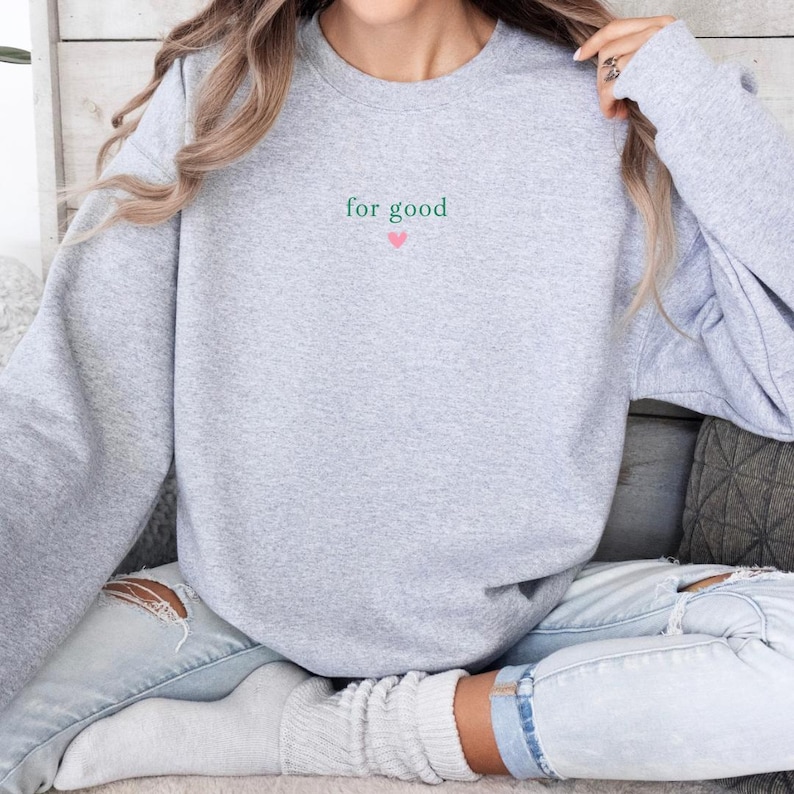 May include: Gray sweatshirt with the text "for good" in green with a small pink heart below it.