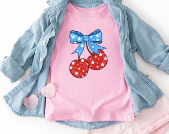 Camiseta Coquette com Laço de Cereja para o 4 de Julho | Camiseta Patriótica com Estampa de Estrelas e Listras | Camiseta Infantil e Juvenil Fofa para Férias de Verão nos EUA