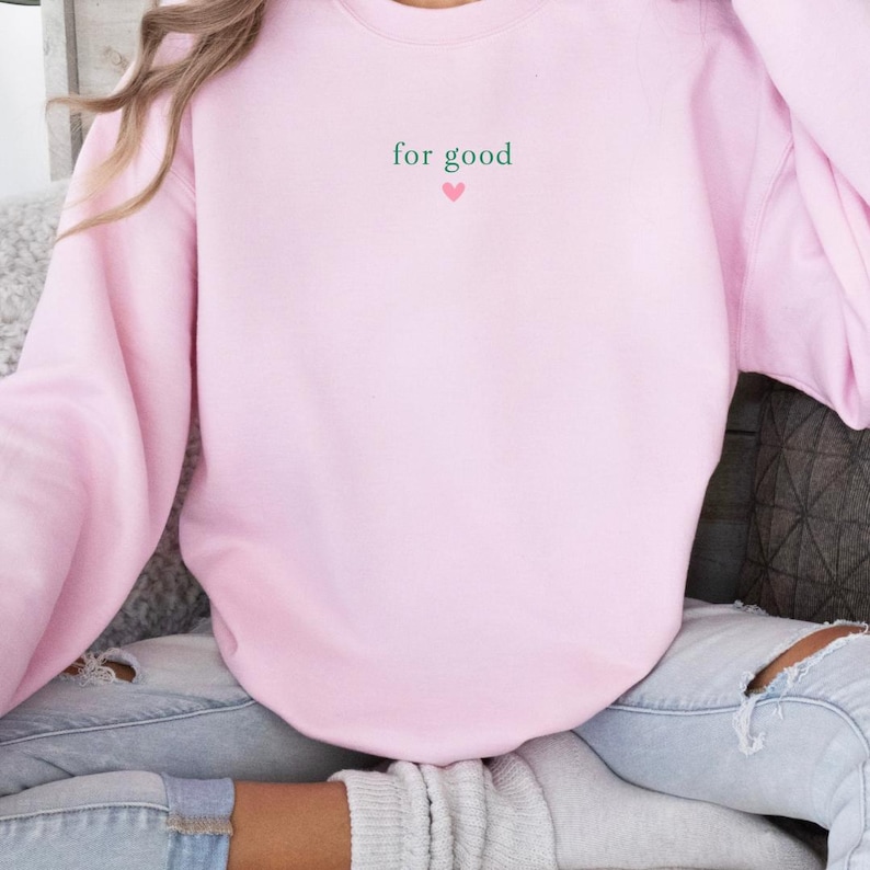 May include: Pink sweatshirt with the text "for good" and a small pink heart.