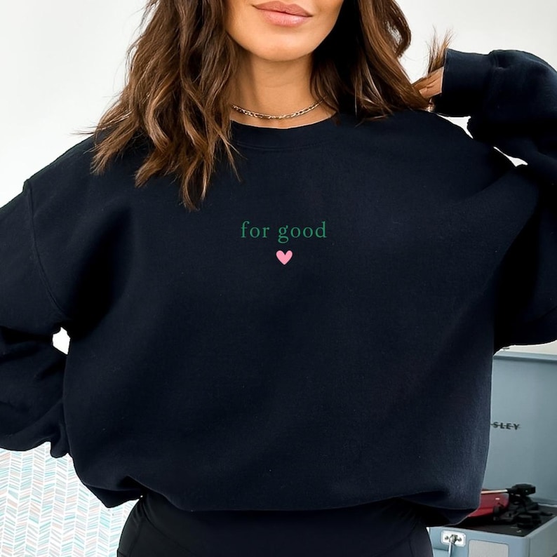 May include: Black sweatshirt with the text "for good" in green and a small pink heart.