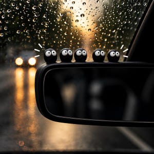 May include: A car side mirror with a row of black, round, cartoon-like figures with white eyes and a smiling expression. The background shows a rainy day with blurred headlights and a sunset.