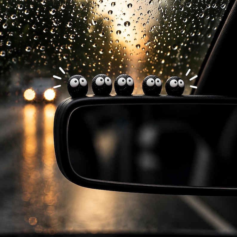 May include: A car side mirror with a row of black, round, cartoon-like figures with white eyes and a smiling expression. The background shows a rainy day with blurred headlights and a sunset.