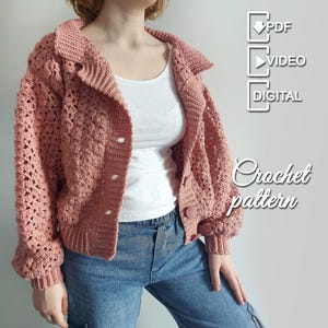 Puede incluir: Una chaqueta de ganchillo rosa polvoriento con cuello y cierre de botones. La chaqueta presenta un patrón de puntadas texturizadas y se combina con vaqueros azules. La imagen incluye el texto "Crochet pattern" e iconos para PDF, vídeo y formatos digitales.
