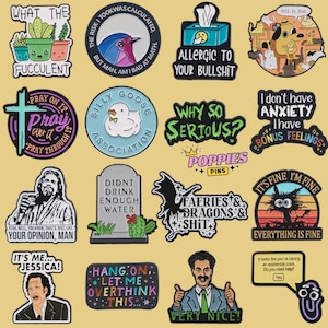 May include: A collection of colorful enamel pins with various humorous phrases and images. Designs include cacti, a bird, a duck, a tombstone, and the phrases "Why So Serious?" and "It's Fine, I'm Fine".