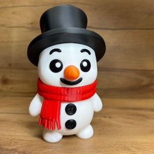 May include: A white snowman figurine featuring a black top hat, a bright orange carrot-shaped nose, and a red scarf wrapped around its neck. The snowman has two black circular buttons on its torso, black eyes, and a black curved mouth.