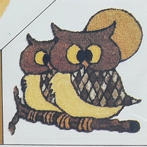 May include: A whimsical illustration of two owls perched on a branch, set against a textured yellow moon. The owls feature brown and white patterned feathers, large yellow eyes, and are sitting on a brown branch. The artwork has a folk art style.