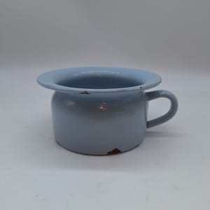 Op de afbeelding: Een lichtblauwe emaille chamberpot met een handvat. De pot heeft een brede rand en vertoont tekenen van slijtage.