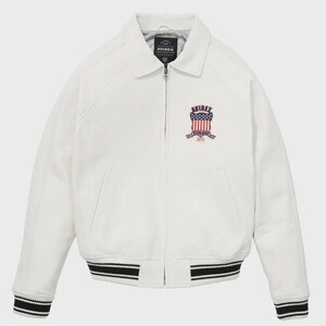 Puede incluir: Chaqueta blanca con cuello y cierre de cremallera. La chaqueta presenta un dobladillo y pu&ntilde;os a rayas blancas y negras. Un emblema con el texto "AVIREX" y un dise&ntilde;o de bandera americana est&aacute; en el pecho.