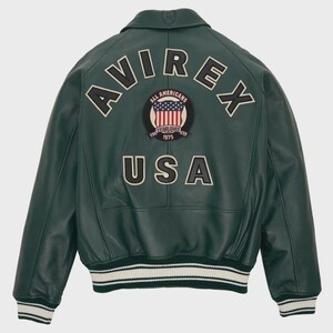 Puede incluir: Chaqueta de cuero verde oscuro con la palabra "AVIREX" arqueada en la parte superior de la espalda. Debajo, un parche con las palabras "ALL AMERICANS" y "ESTABLISHED 1975" rodeando una bandera estadounidense. La palabra "USA" est&aacute; debajo. La chaqueta tiene pu&ntilde;os y dobladillo a rayas blancas y negras.