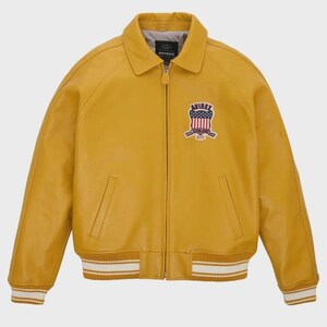 Puede incluir: Chaqueta de cuero amarillo mostaza con cremallera frontal, cuello y pu&ntilde;os y dobladillo acanalados. Cuenta con un parche en el pecho con un dise&ntilde;o de escudo y la palabra "AVIREX". La chaqueta tiene dos bolsillos delanteros.