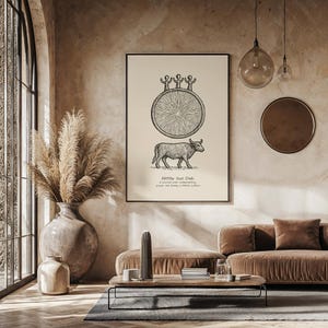 Puede incluir: Un cuadro enmarcado con una ilustración en blanco y negro de un disco solar y un toro. El texto "Hittite Sun Disk" está debajo del toro. El cuadro cuelga sobre un sofá marrón en una habitación con una ventana grande y un jarrón decorativo.