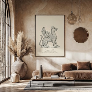May include: A framed print featuring a detailed black and white illustration of a Phrygian Griffin. The artwork is displayed on a cream-colored background with text below. The print is in a black frame, displayed in a living room setting.
