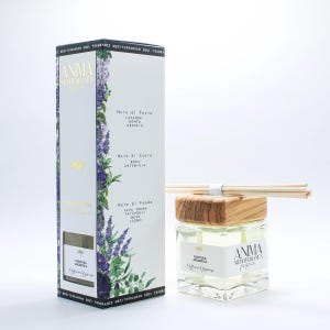 Może przedstawiać: Dyfuzor zapachowy z białym pudełkiem i szklaną butelką. Pudełko zawiera napis "ANIMA Mediterranea" i kwiatowe wzory. Butelka ma drewnianą nakrętkę i ten sam tekst. Artykuł do dekoracji wnętrz.
