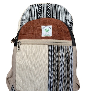 Può includere: Zaino in canapa con vari motivi tessuti in nero, bianco, marrone e beige. La sezione superiore presenta una cerniera nera e un pannello marrone con l'etichetta "Himalayan Hemp THC Free Made in Nepal".