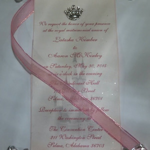May include: A pink scroll wedding invitation with a silver crown and a castle graphic. The invitation reads "We request the honor of your presence at the royal matrimonial union of Latasha Kimber to Aaron McKinley on Saturday, May 30, 2015 at six o'clock in the evening The Serdivant Hall 711 Bailey Street Selma, Alabama 36701 Reception to immediately follow the ceremony at The Convention Center 211 Washington Street Selma, Alabama 36703"
